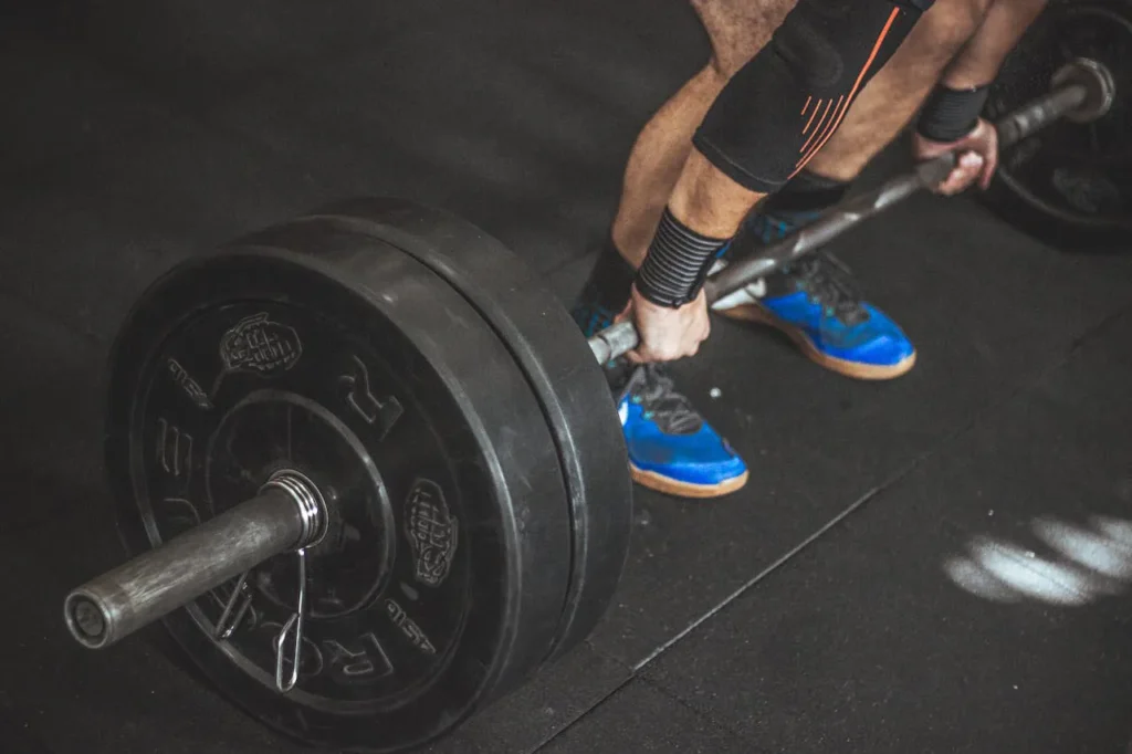 Close-up van een sporter die een zware halterstang met gewichtsschijven vastgrijpt voor het deadliften .