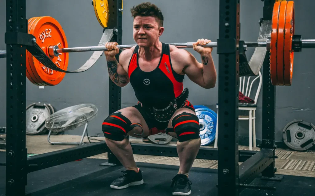 Een sporter is zwaar aan het squatten in een power rack, met een halterstang vol gewichten op de schouders.