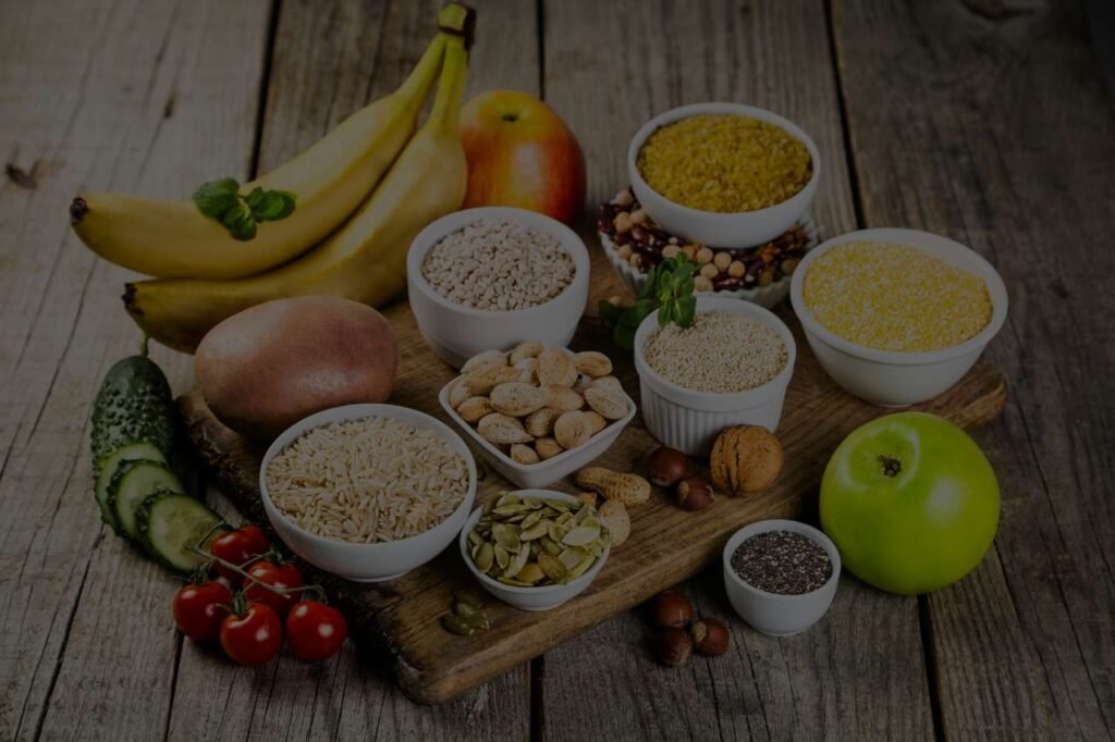 Een selectie van volkoren granen, fruit en zaden rijk aan koolhydraten, uitgestald op een houten ondergrond.